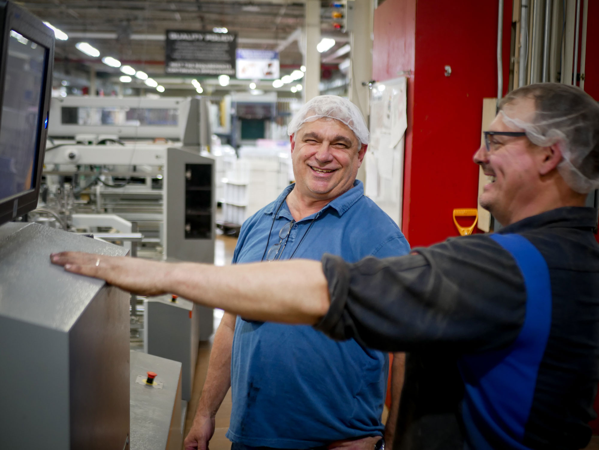Two MOD PAC employees laugh on the manufacturing floor