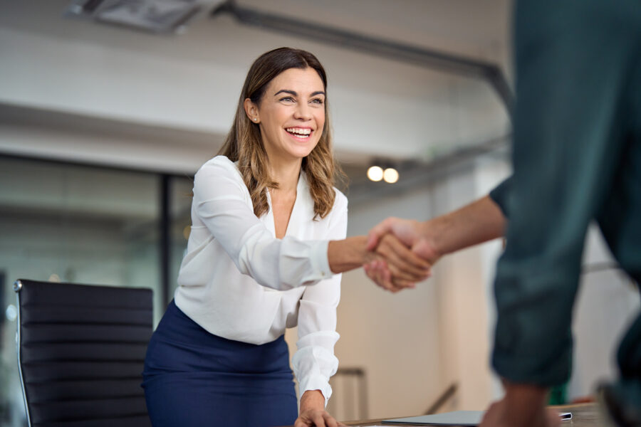 person reaches across desk to shake another's hand